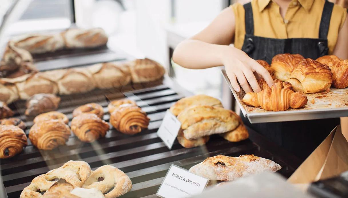 A baker sets up a display of freshly-baked pastries